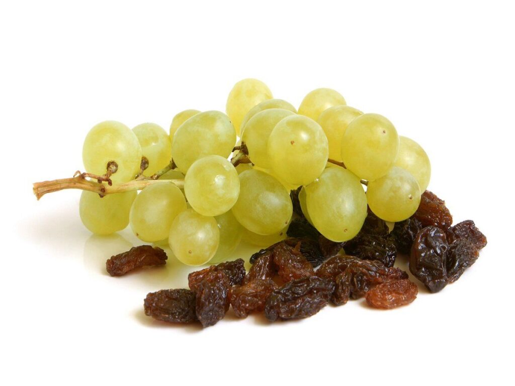 a bunch of green grapes next to raisins.